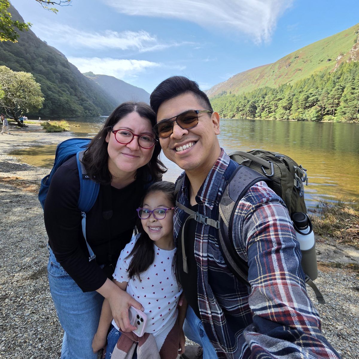 Sergei with his wife and daughter, smiling on a lakeside hike in Ireland
